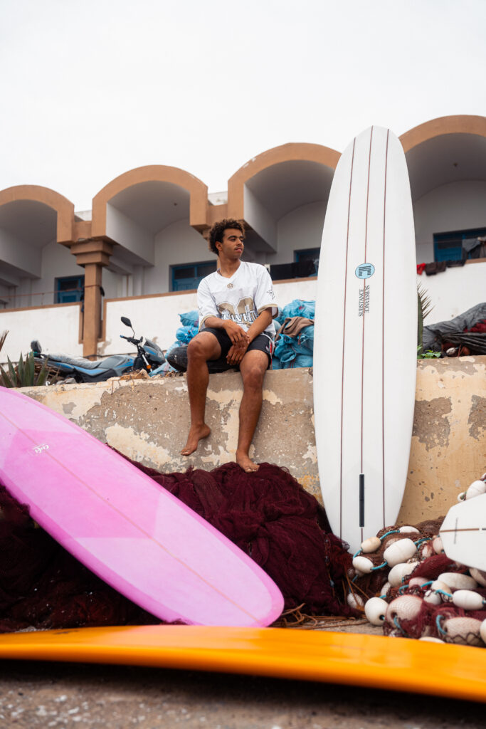 Moroccan local sitting in between three colorful classic longboards.